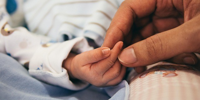 baby og forældre holder hånd